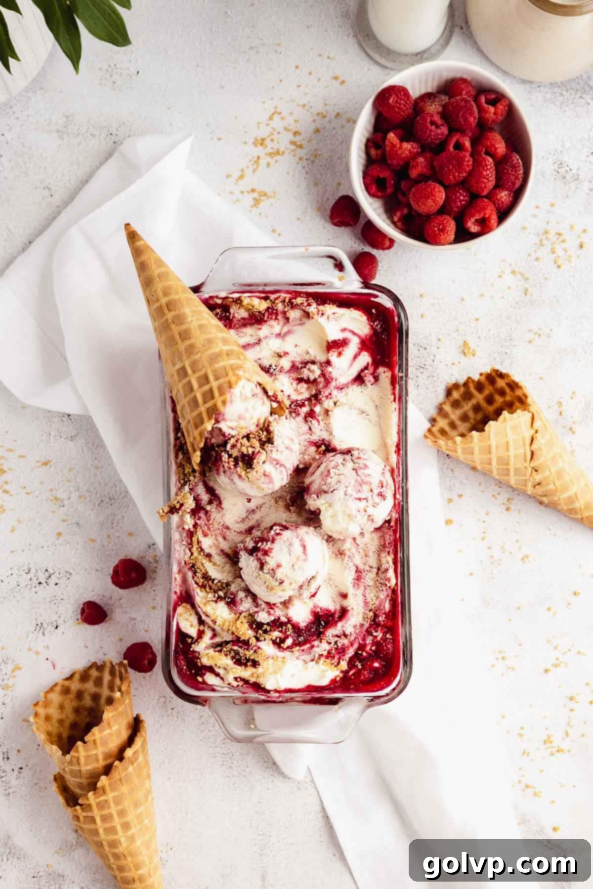 Scooped raspberry cheesecake ice cream with visible ribbons of raspberry and graham crumbs
