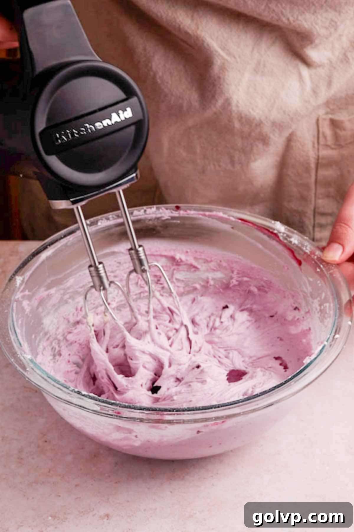Beating blueberry cream cheese frosting ingredients with an electric mixer until fluffy and light