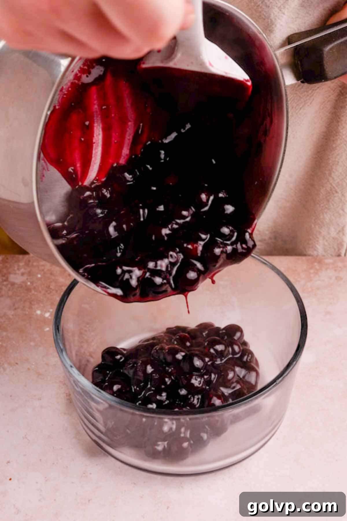 Pouring hot blueberry filling into a non-metal bowl to cool completely and prevent reactions