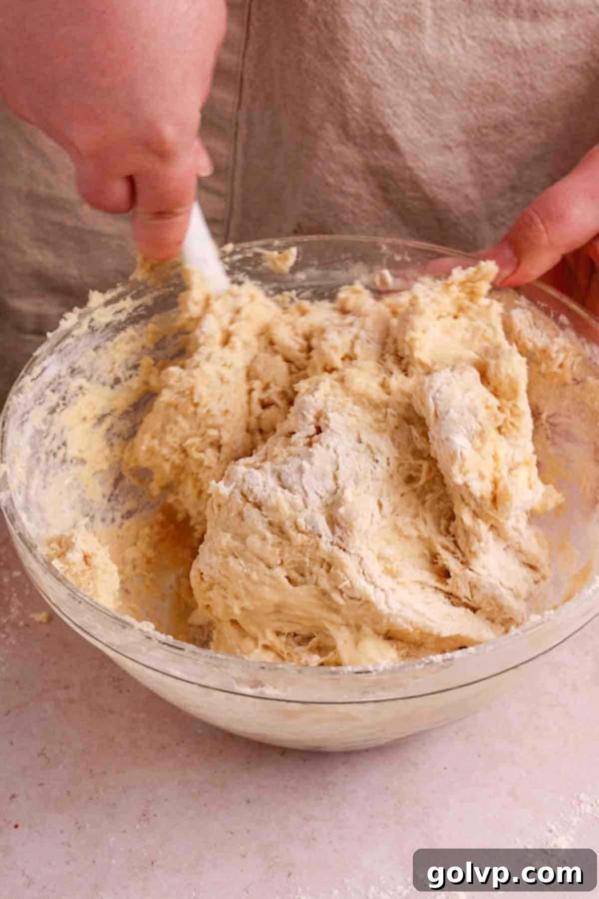 Mixing the shaggy, sticky no-knead dough in a large bowl with a spoon