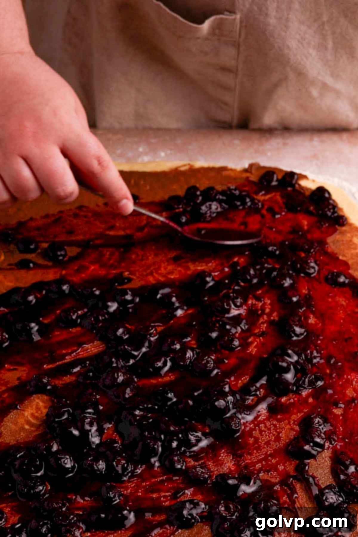 Spreading blueberry filling evenly over the rolled-out dough rectangle