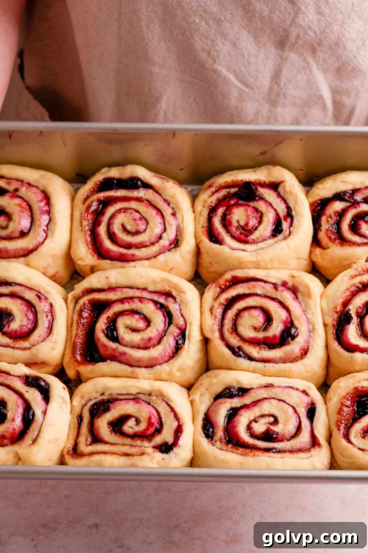 Risen cinnamon rolls, puffy and filling the gaps in the baking pan, ready to bake