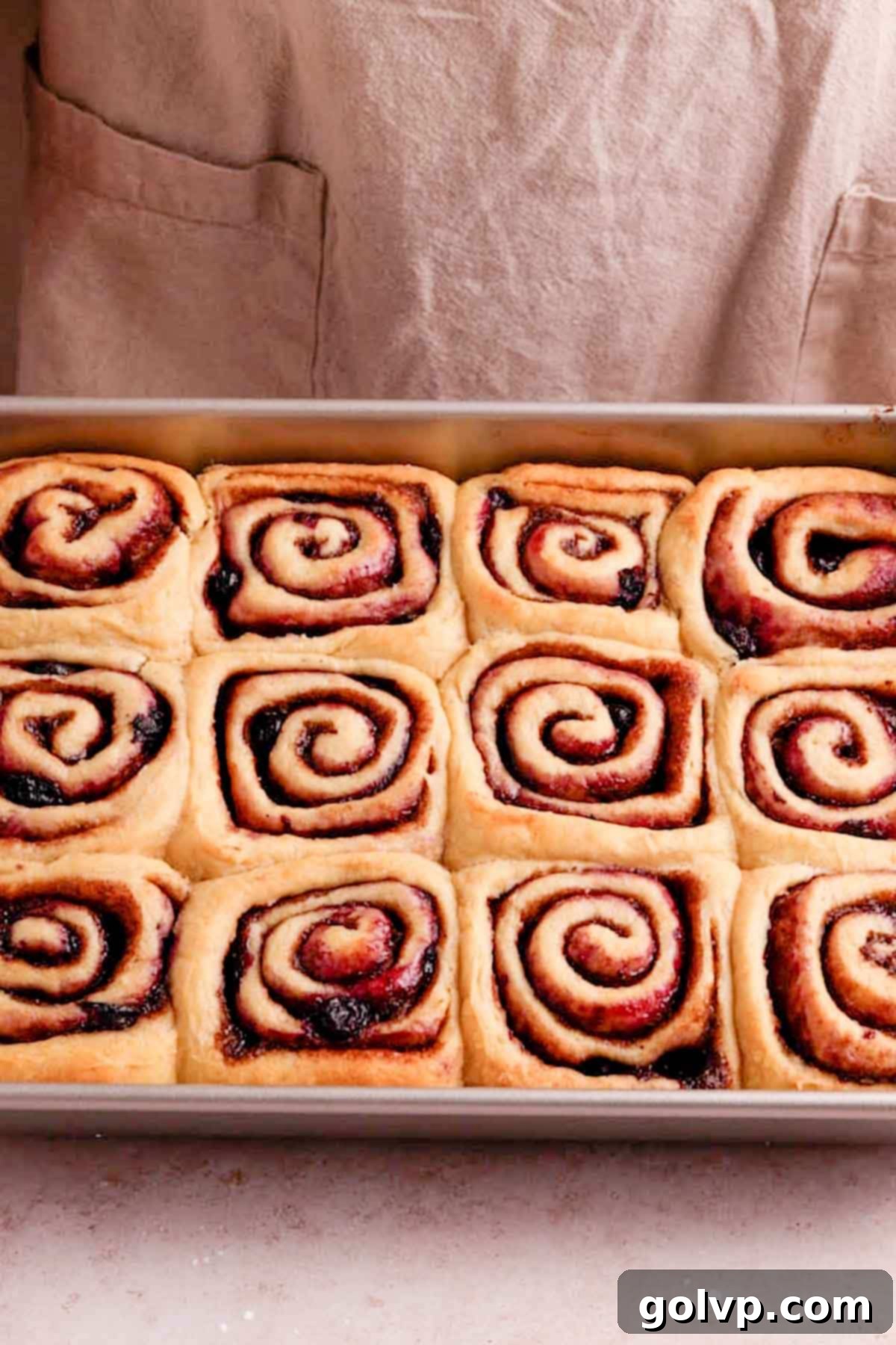Freshly baked blueberry cinnamon rolls, golden brown and without frosting, cooling in the pan