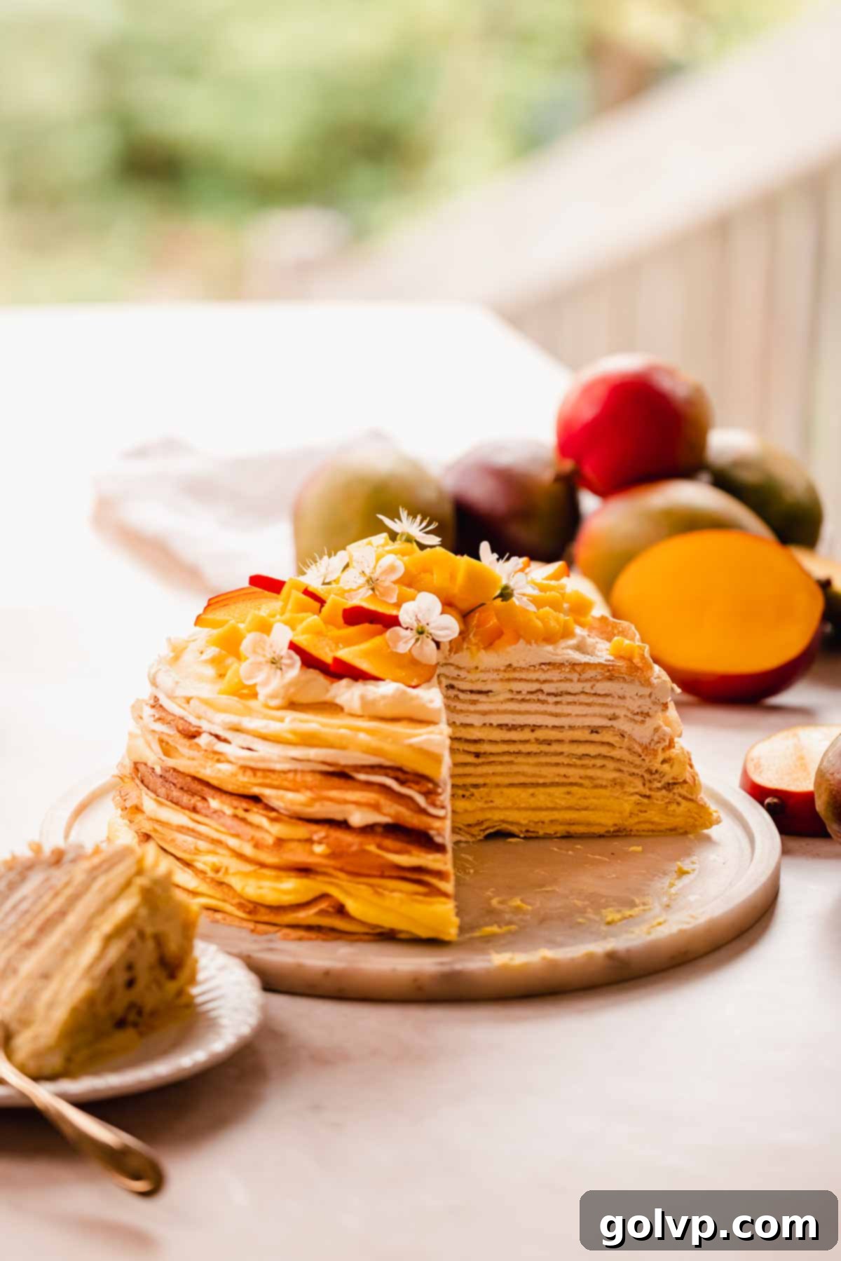 Decadent Mango Crepe Cake, Made Easy 2 A beautifully cut slice of mango crepe cake revealing its many layers, with fresh mango slices on top.