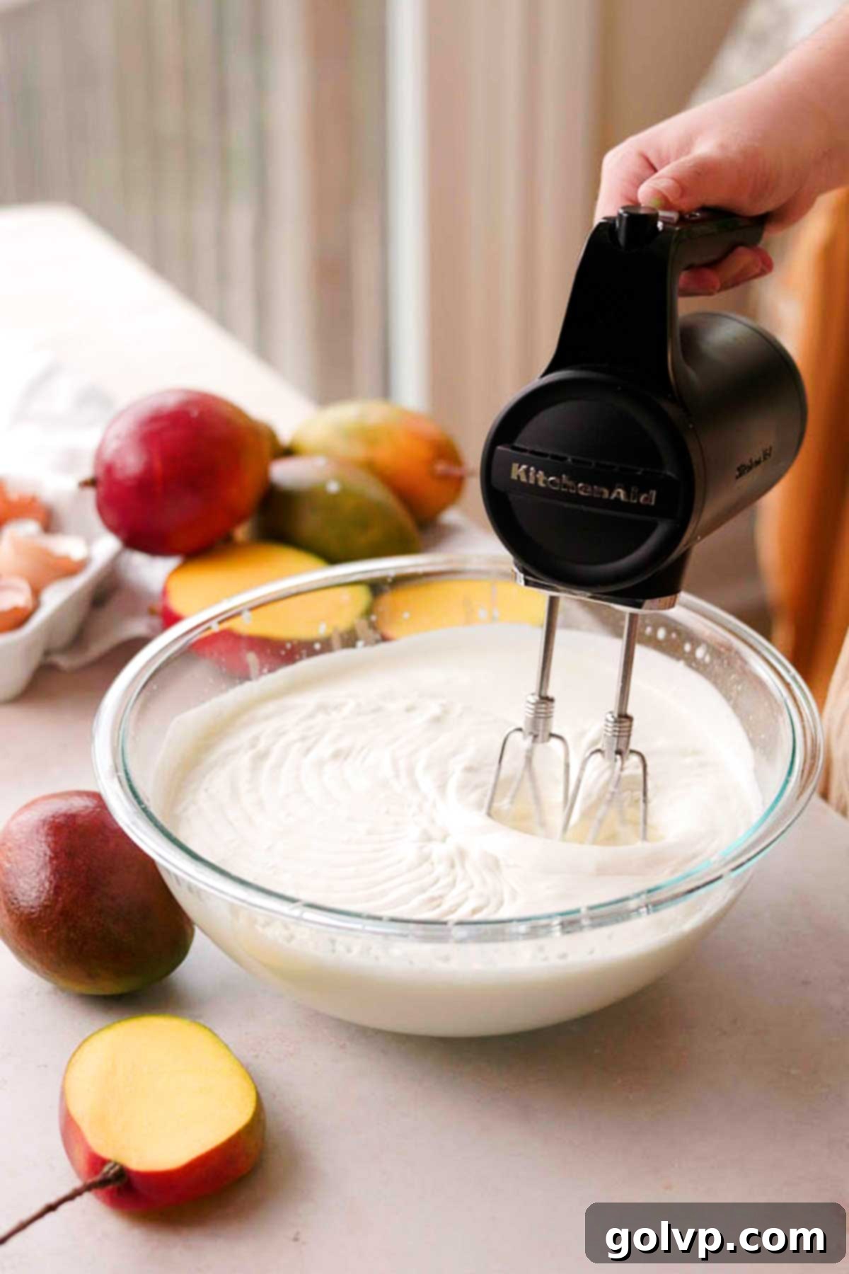 Decadent Mango Crepe Cake, Made Easy 11 Whipping cold heavy cream in a glass bowl with an electric mixer.