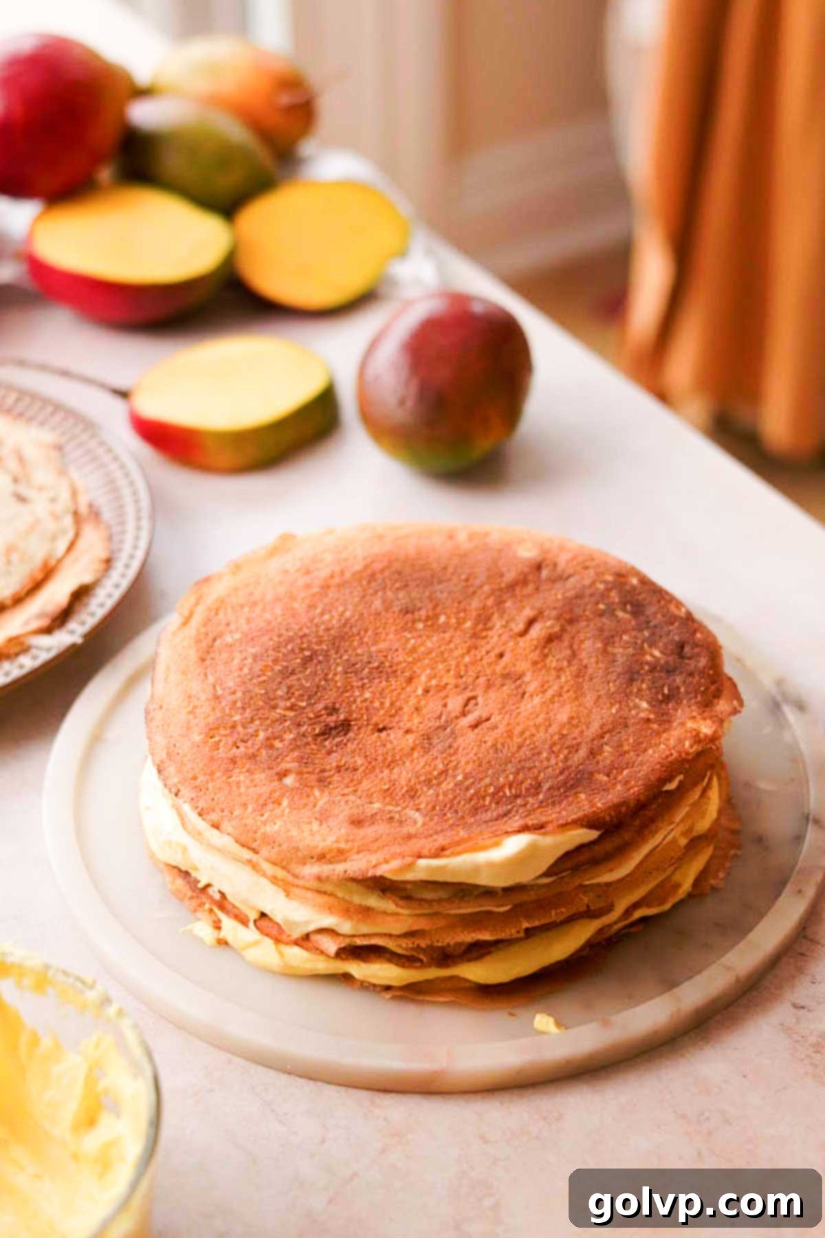 Decadent Mango Crepe Cake, Made Easy 15 Layering crepes and different shades of mango cream to create an ombré effect.