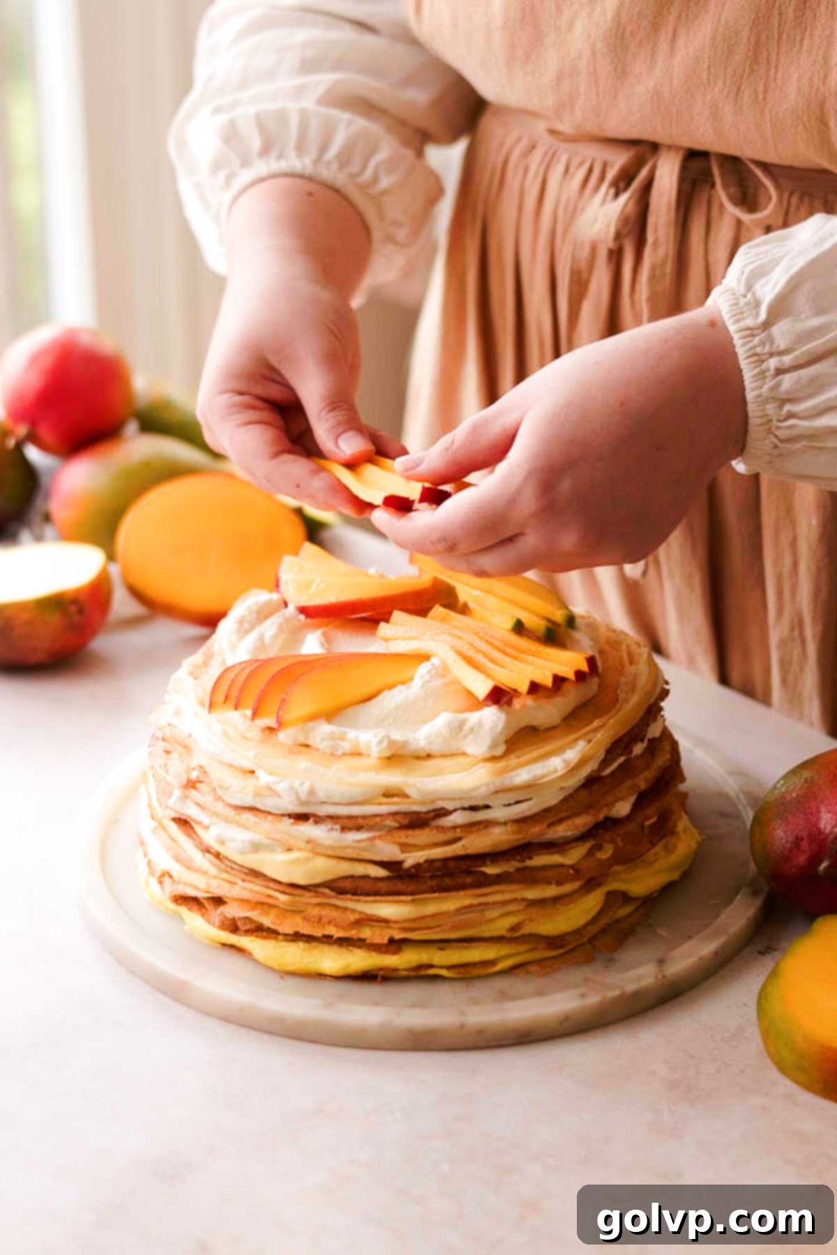 Decadent Mango Crepe Cake, Made Easy 17 The assembled mango crepe cake topped with fresh mango slices and edible flowers.
