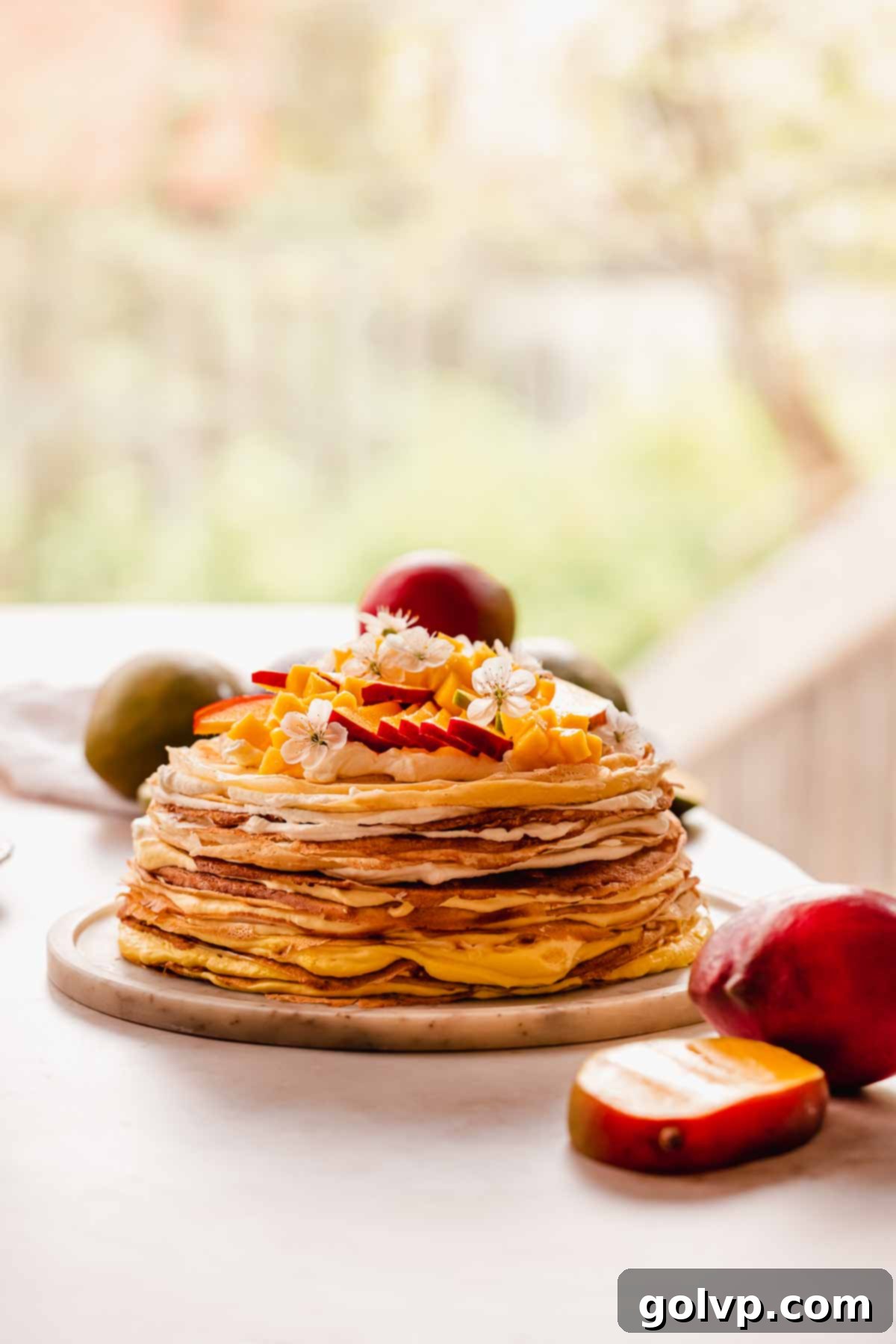 Decadent Mango Crepe Cake, Made Easy 18 A vibrant mango crepe cake with fresh mango slices and edible flowers, ready to serve.
