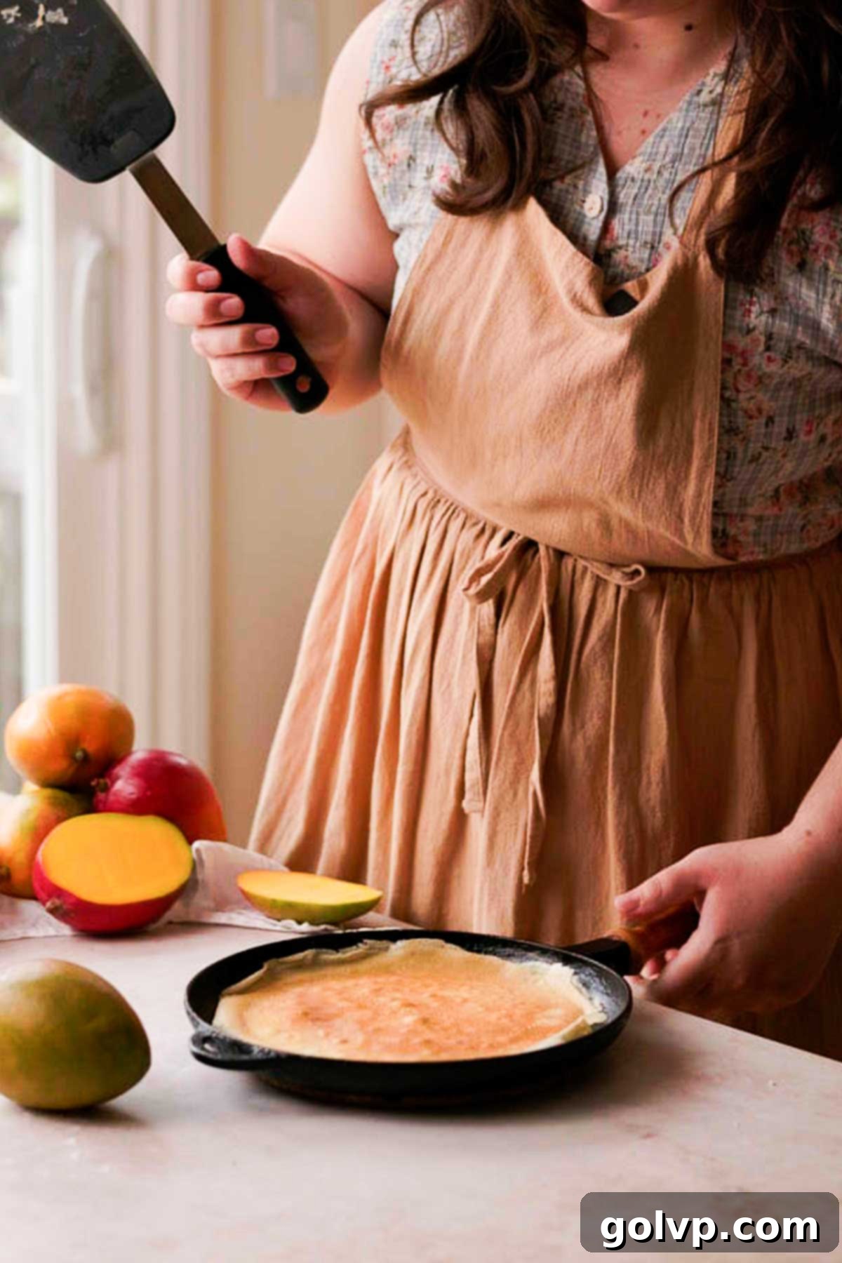 Decadent Mango Crepe Cake, Made Easy 8 A perfectly flipped crepe cooking in a cast iron pan.