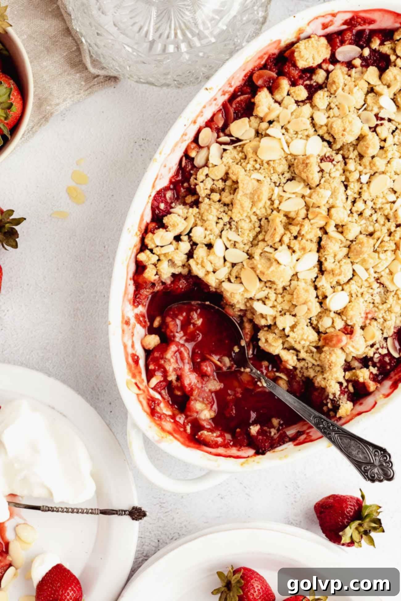Strawberry Almond Crumble served in a baking dish with a scoop missing.