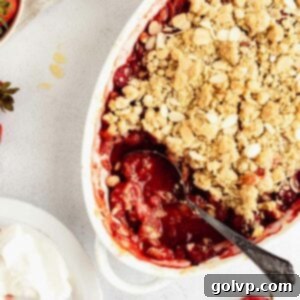 A close-up shot of a baked strawberry almond crumble, showing the golden, crisp topping and bubbling fruit filling.