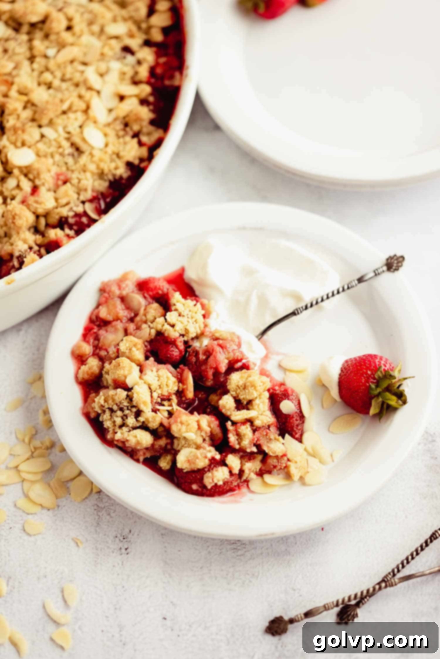 Close-up of baked strawberry almond crumble, showing jammy fruit and golden topping.