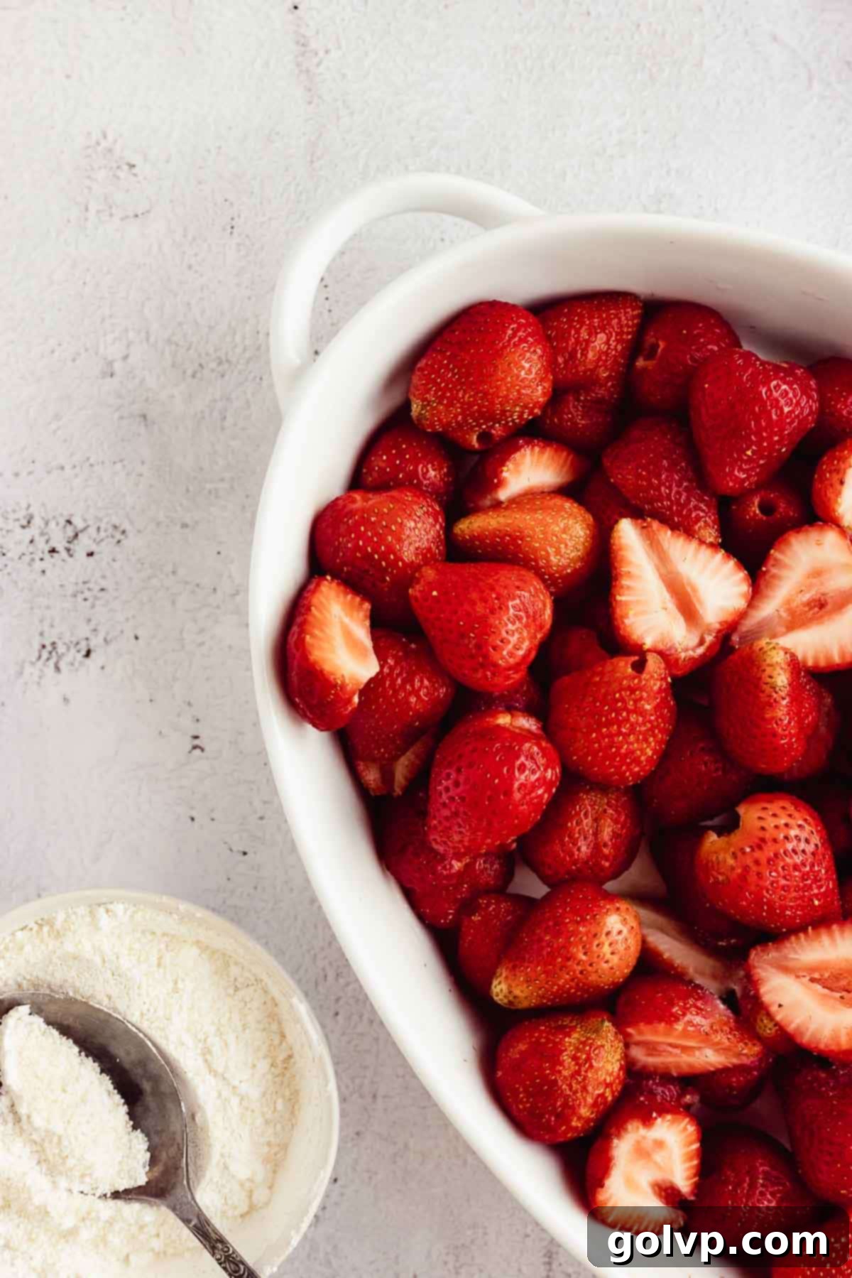 Fresh strawberries in a baking dish, drizzled with lemon juice and sprinkled with sugar-cornstarch mixture.