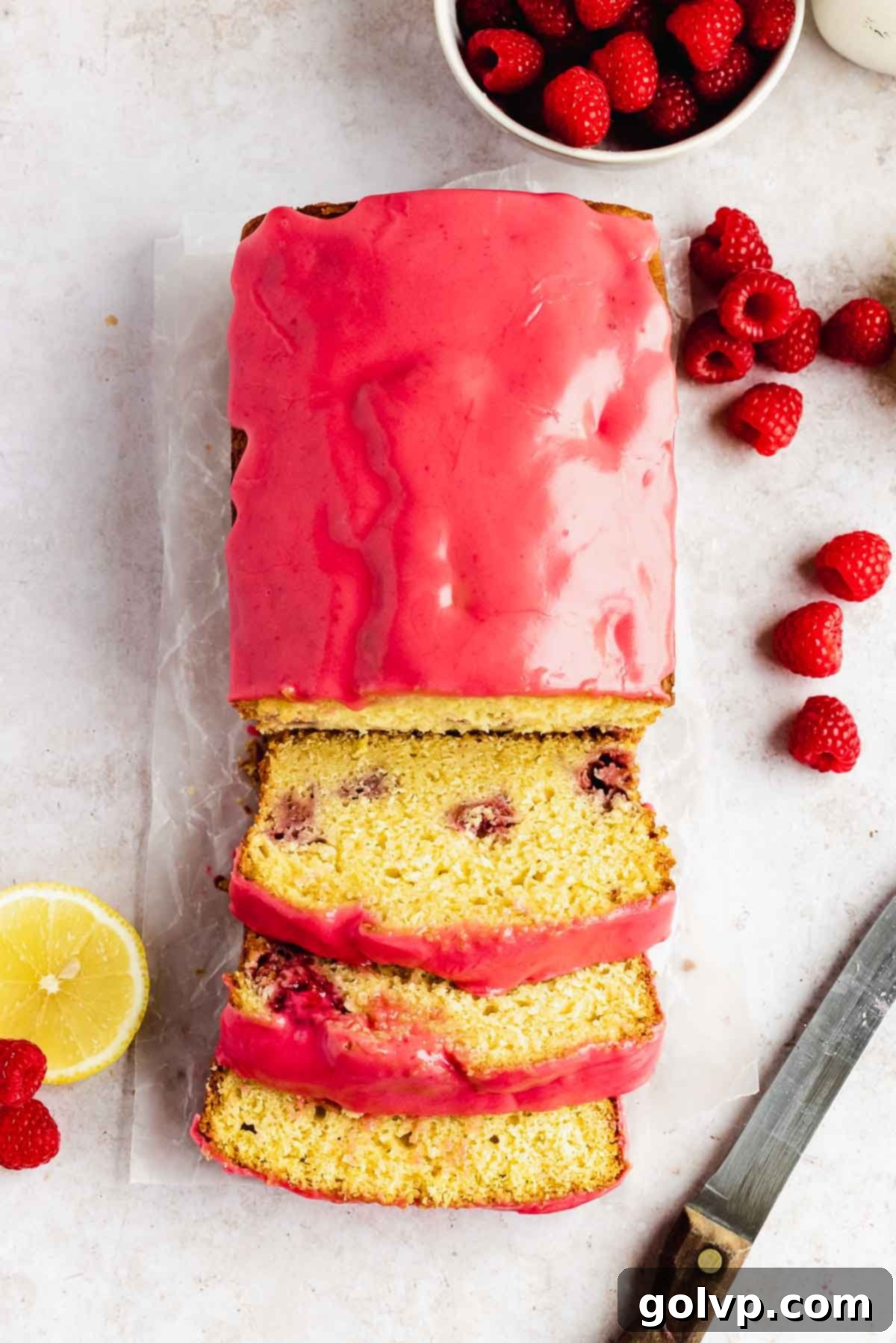 lemon raspberry loaf sliced with raspberry glaze on wax paper