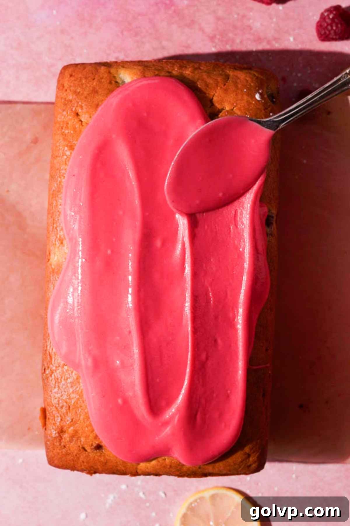 spreading raspberry glaze on top of loaf