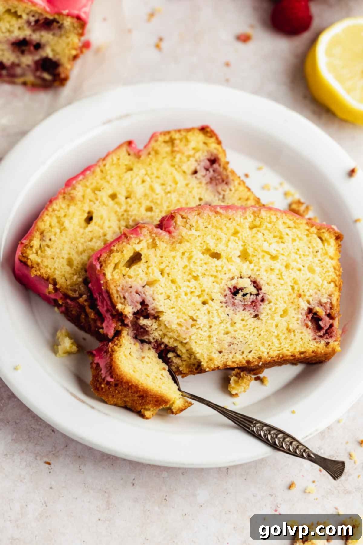 two slices of lemon raspberry loaf on white plate with spoon