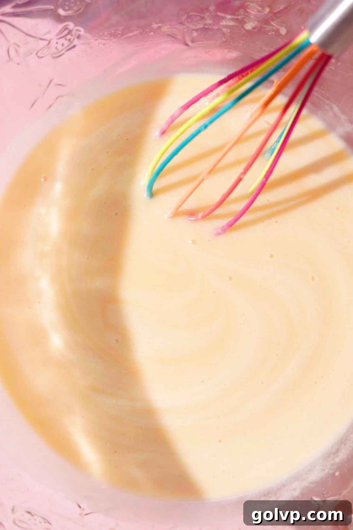whisking wet ingredients in glass bowl with silicone whisk