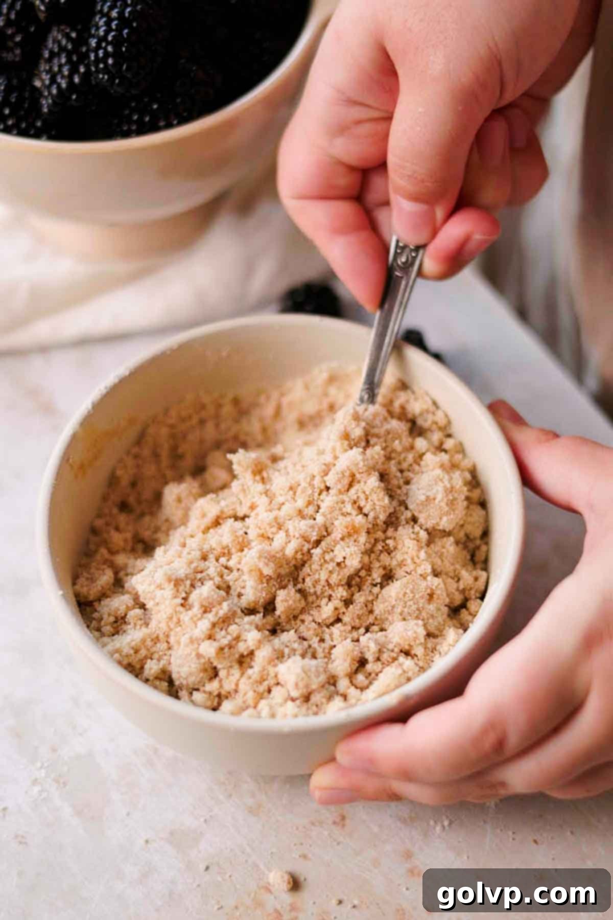 Mixing melted butter into the dry crumble ingredients to form a streusel.