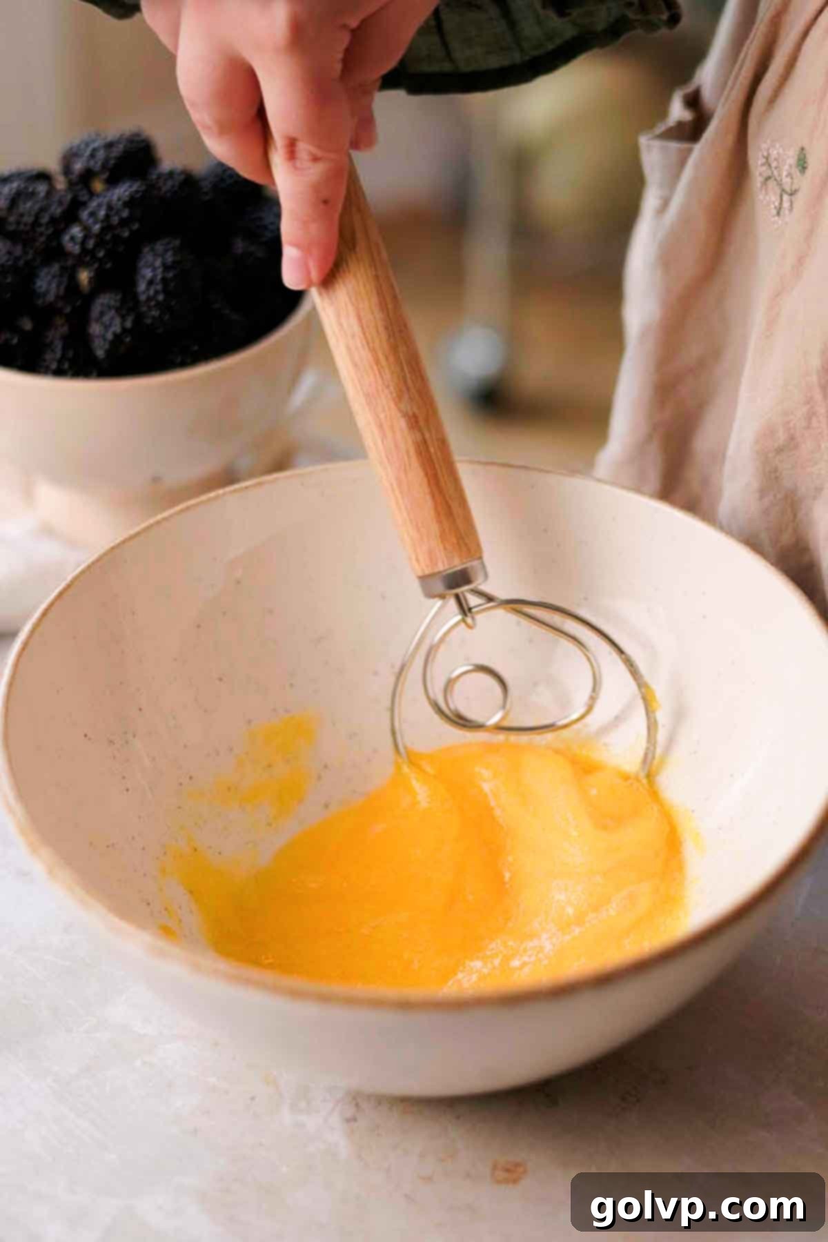 Whisking eggs and granulated sugar together in a large mixing bowl for the muffin batter.