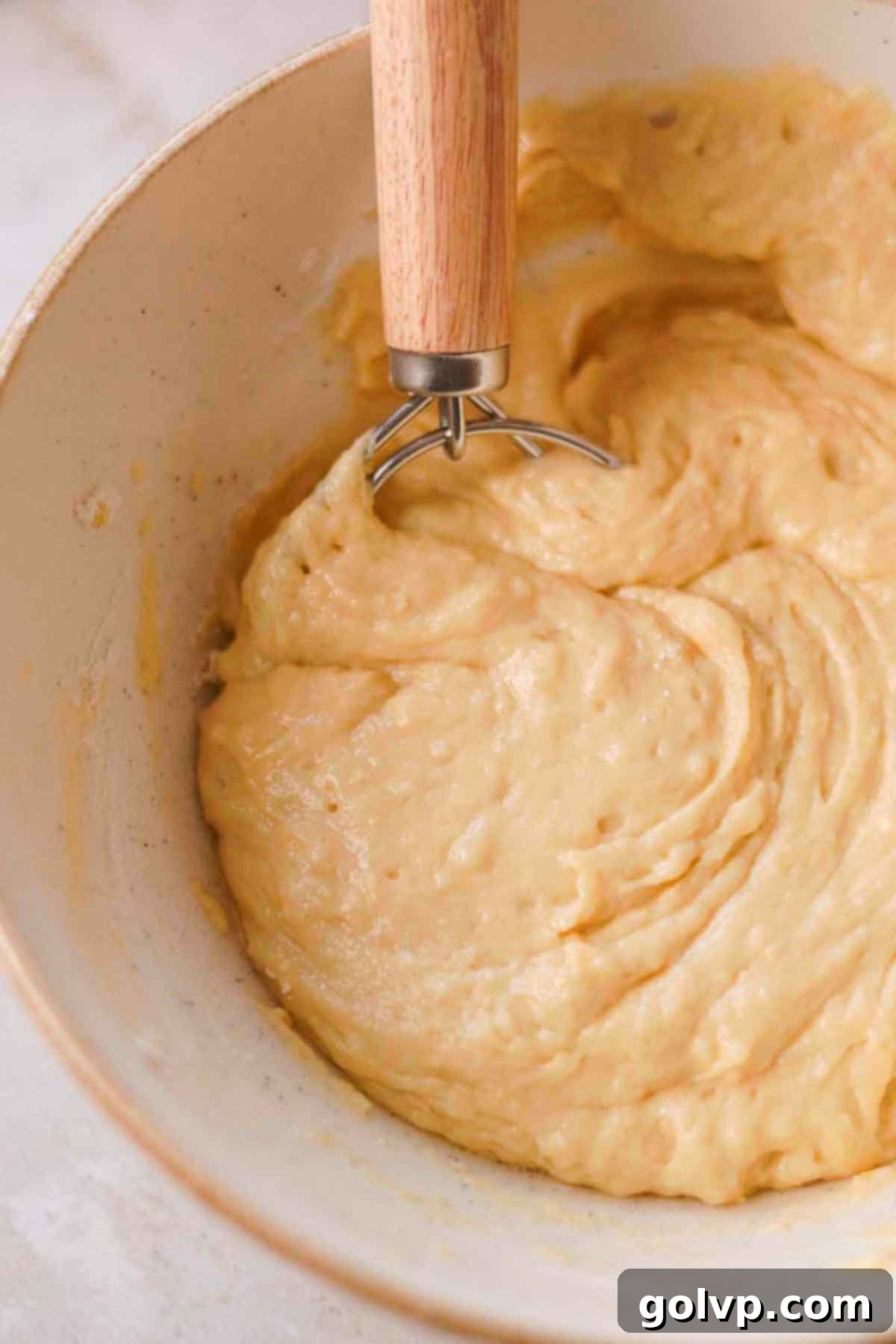 Gently folding flour and baking powder into the wet muffin batter until just combined.