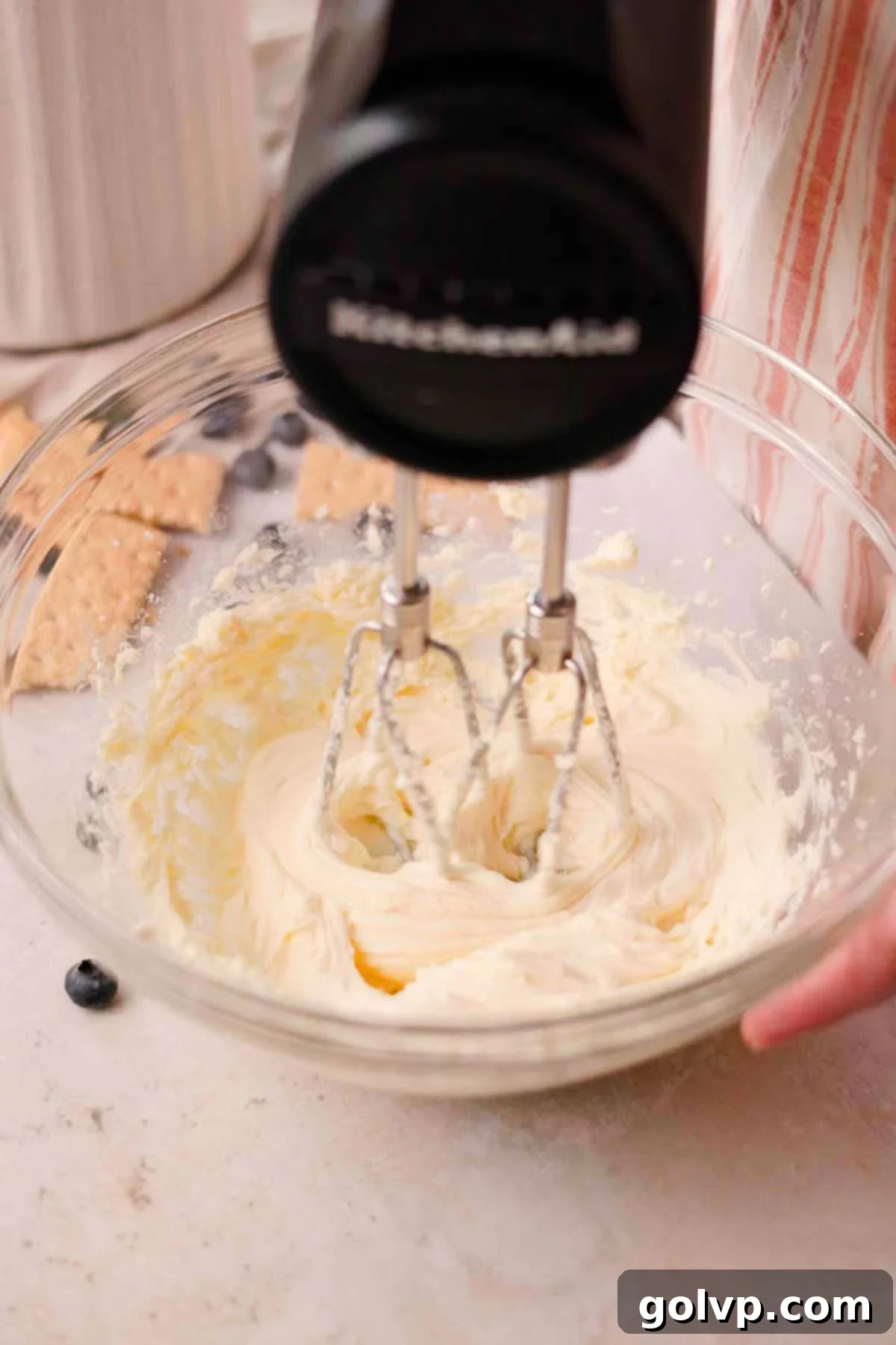 whip cream cheese and sugar in a glass bowl with an electric mixer