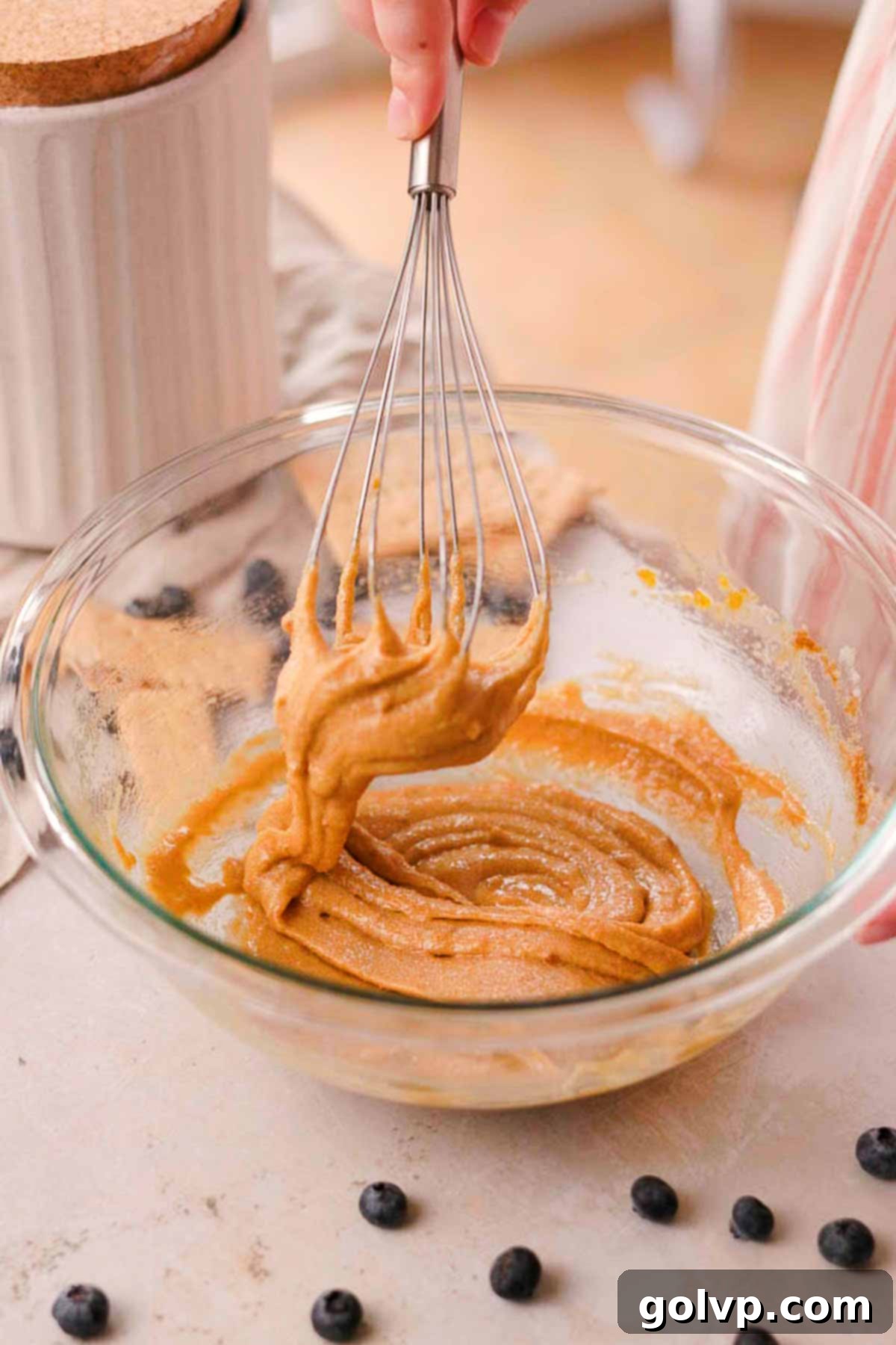whisking sugars and egg in a glass bowl with a wire whisk