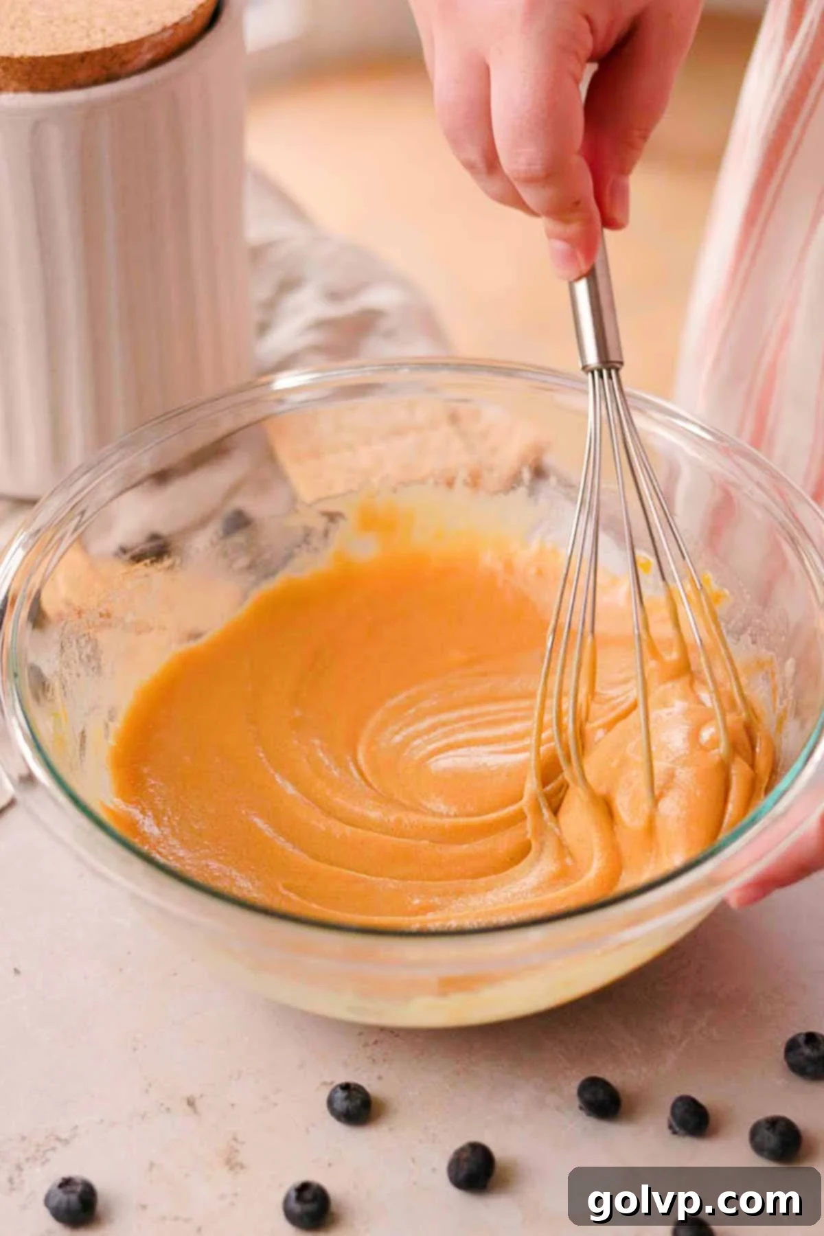 whisking eggs, sugar, and melted butter in a glass bowl with a whisk