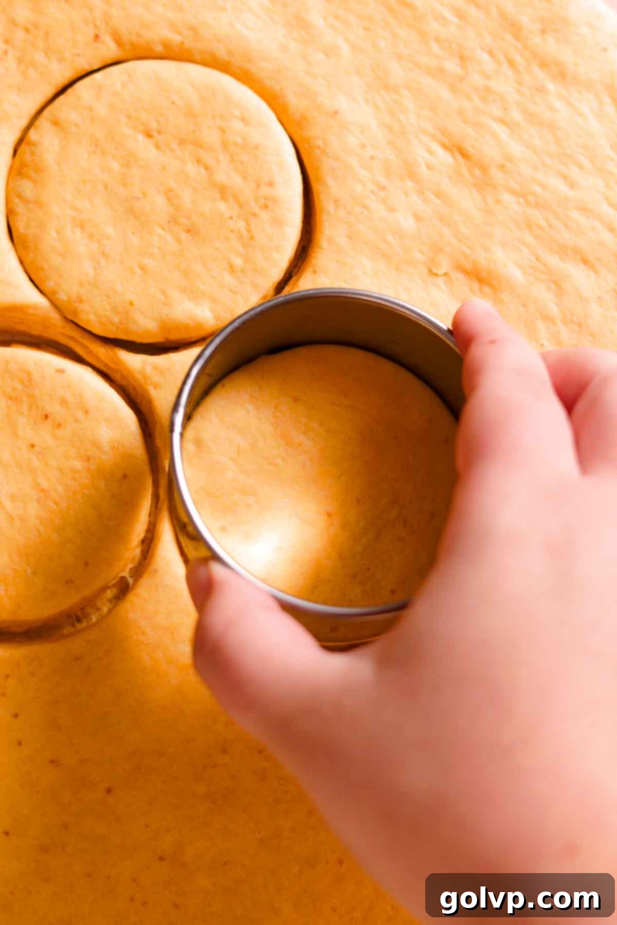 cutting rounds from donut dough with metal round cookie cutter