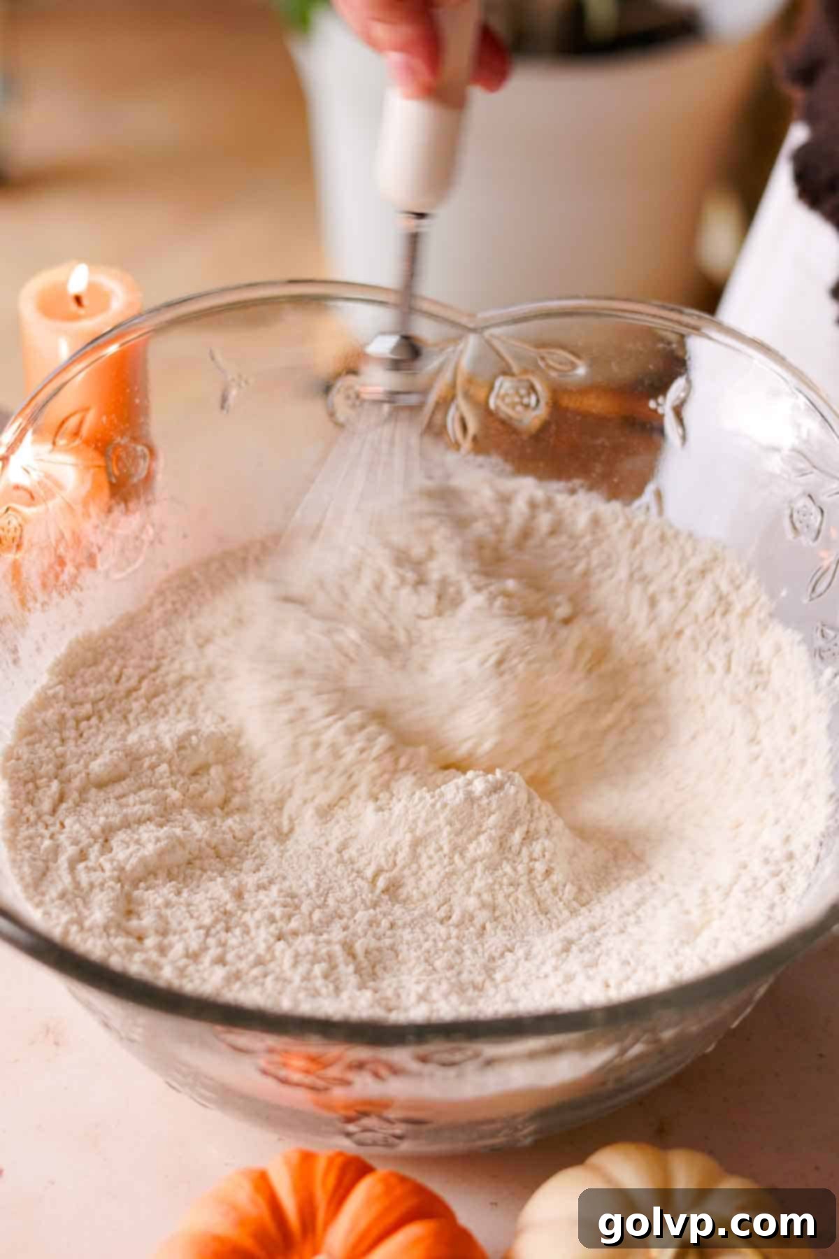 whisking flour by hand in a large glass bowl