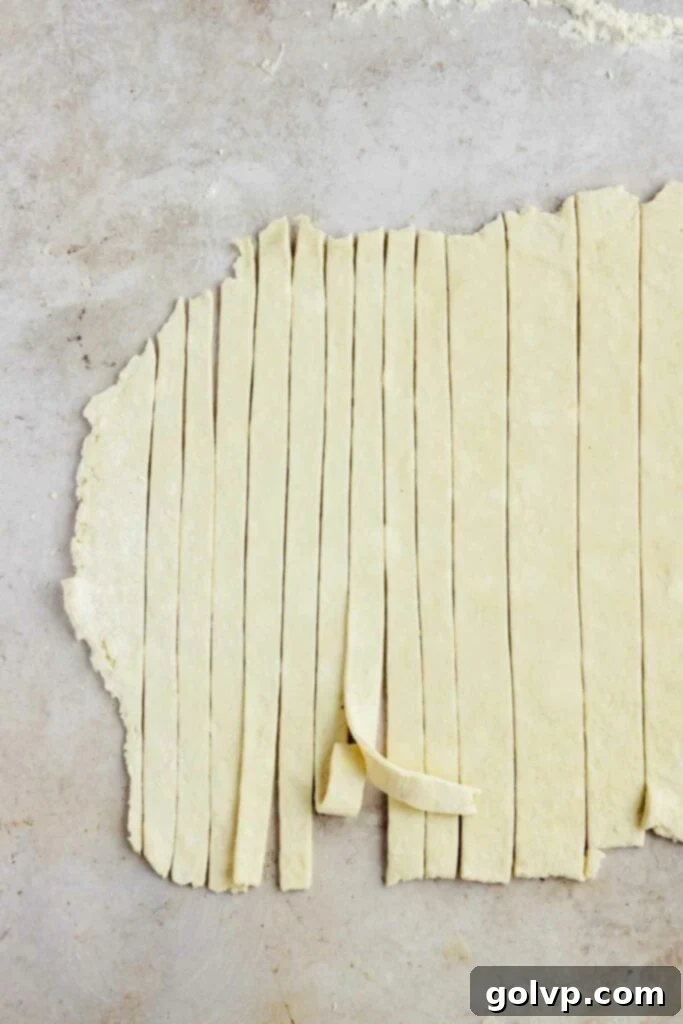 Cutting strips of pie dough for the lattice top of mini blueberry pies.