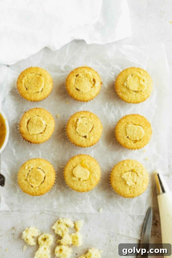 Mango filled cupcakes sealed with small, cut-out pieces of cake before frosting.