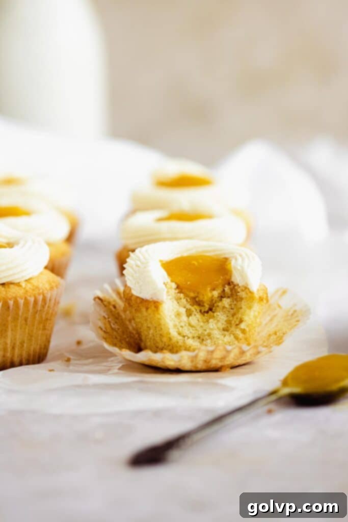 A mango cupcake with a bite taken out, clearly showing the rich, runny mango filling inside the fluffy cake.