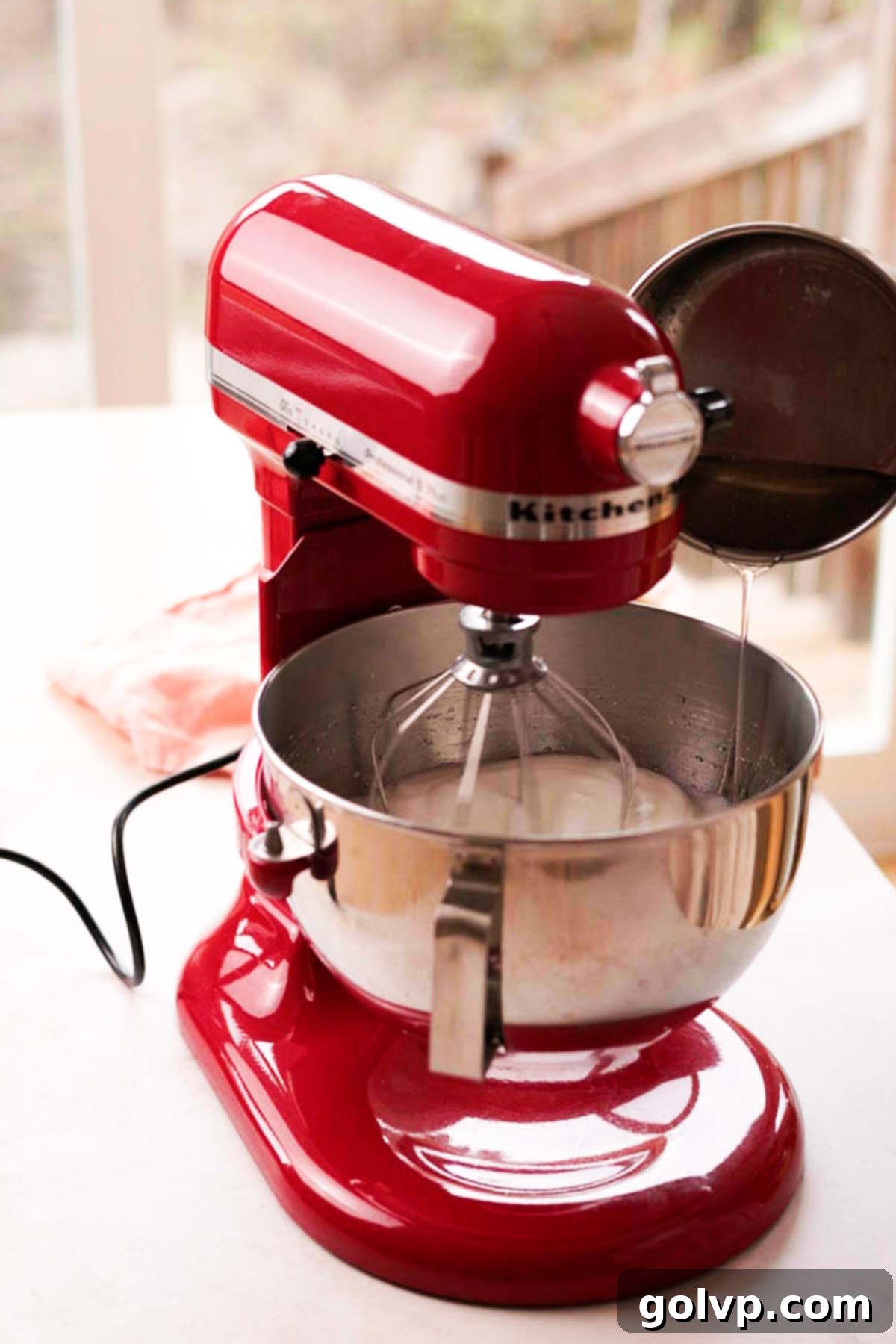 pouring hot sugar syrup into a stand mixer bowl to make italian meringue