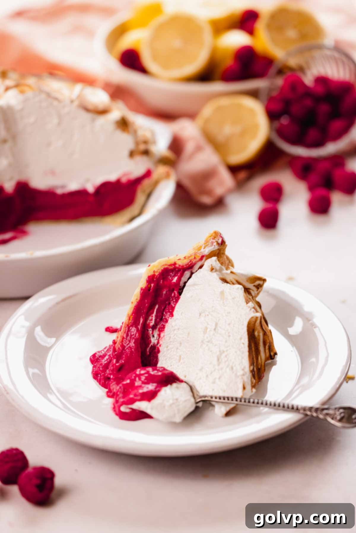 slice of raspberry meringue pie on plate with spoon