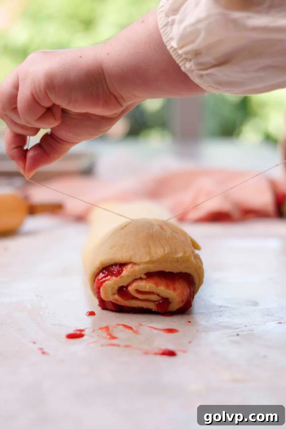 Fresh Strawberry Cinnamon Swirls 15 Cutting the strawberry cinnamon roll log into individual rolls using a piece of string or unflavored floss.