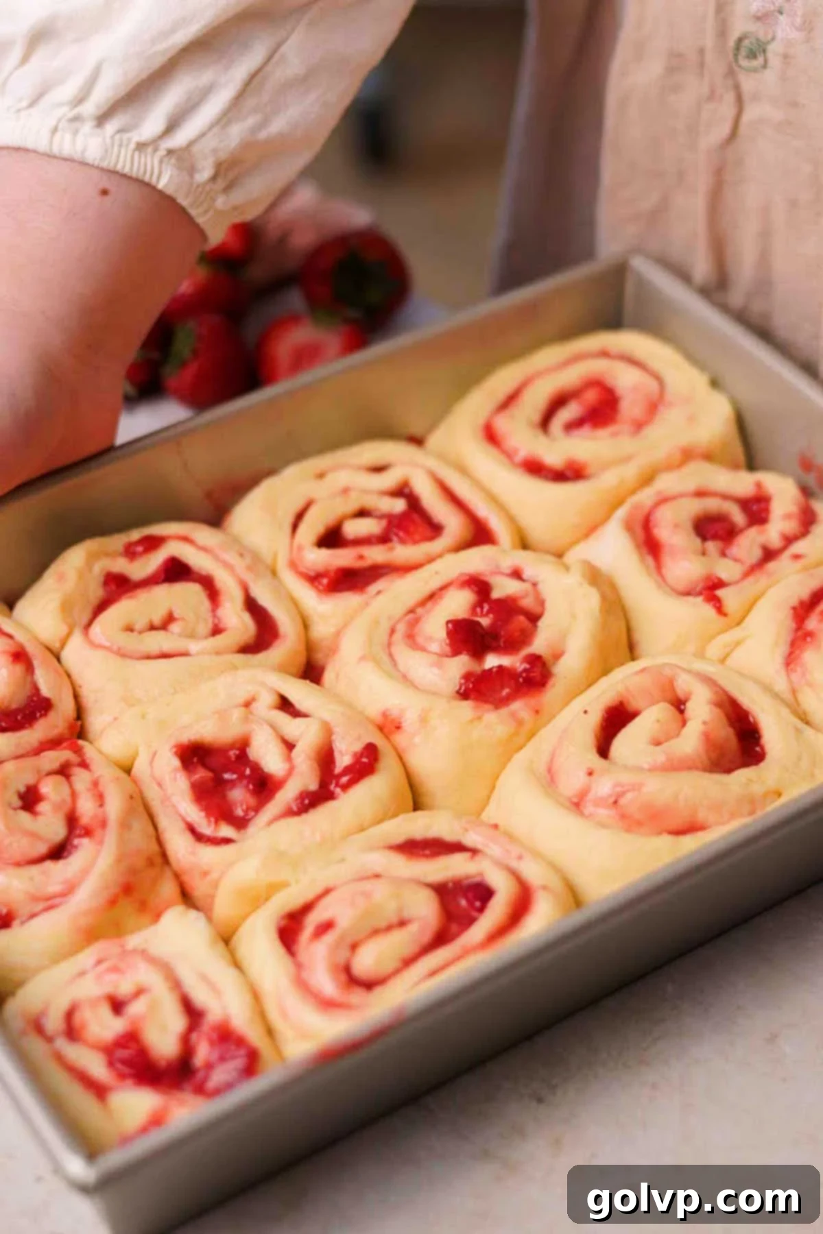 Fresh Strawberry Cinnamon Swirls 16 Assembled strawberry cinnamon rolls, risen and puffy, arranged in a rectangular baking pan before baking.