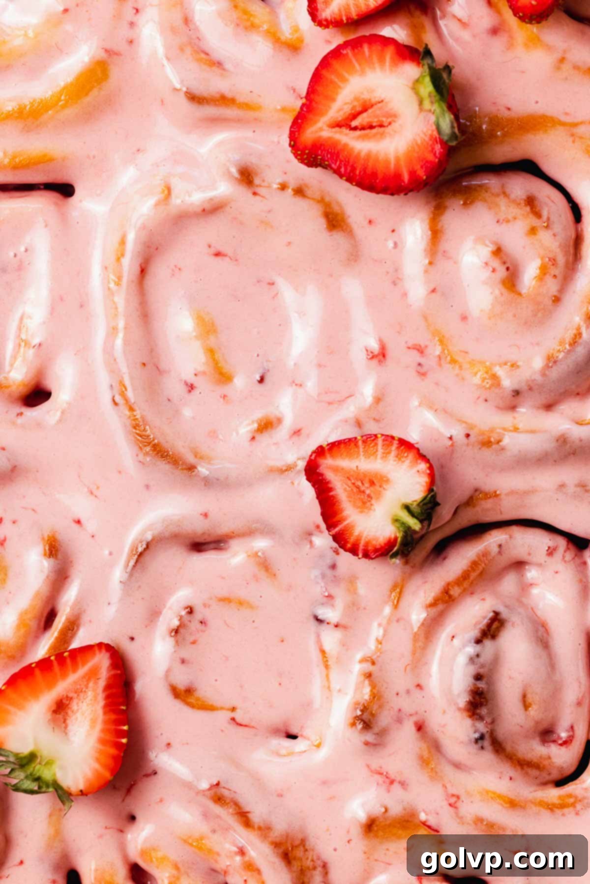 Fresh Strawberry Cinnamon Swirls 21 Close-up of the smooth and tangy strawberry cream cheese glaze spread generously on top of baked strawberry cinnamon rolls.