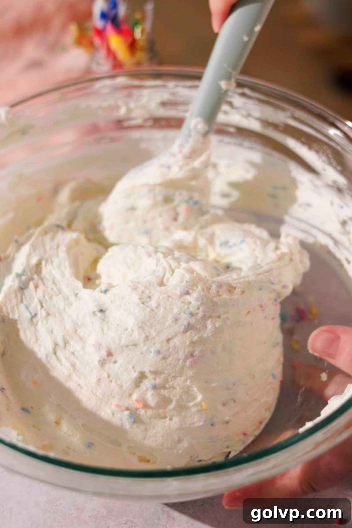 folding colorful sprinkles into the cheesecake filling