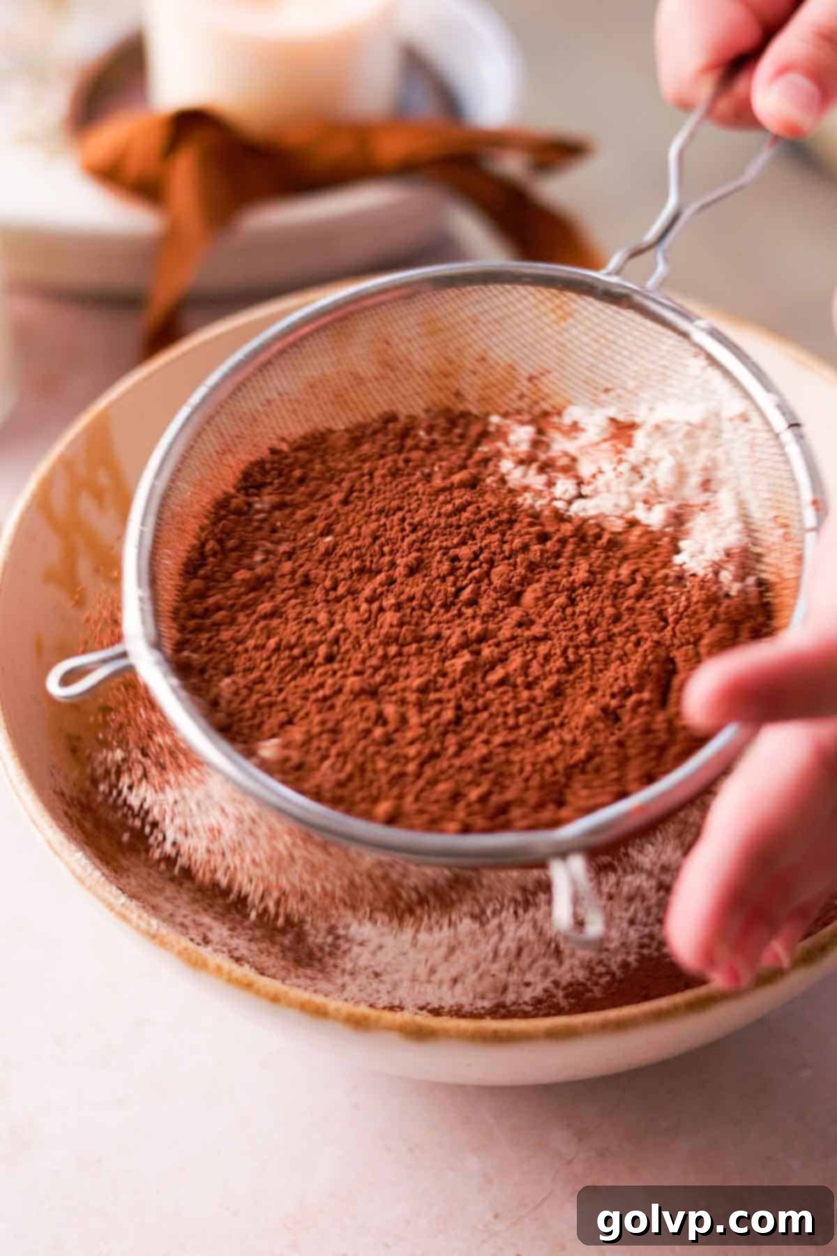 sift flour and cocoa powder into bowl of wet ingredients with wire sieve
