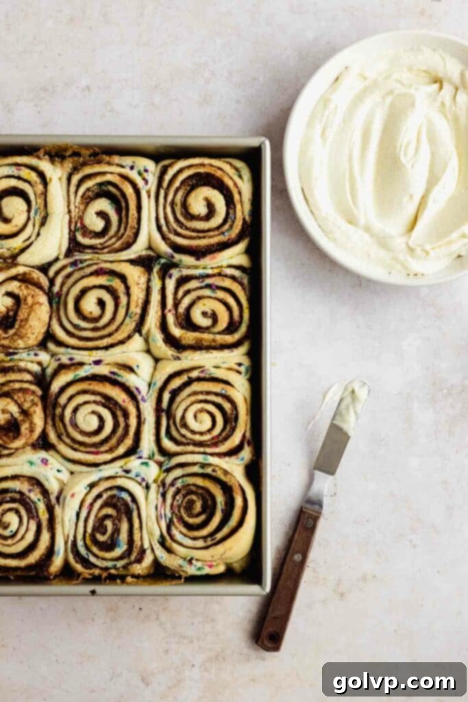 freshly baked funfetti cinnamon rolls with cream cheese frosting in a bowl