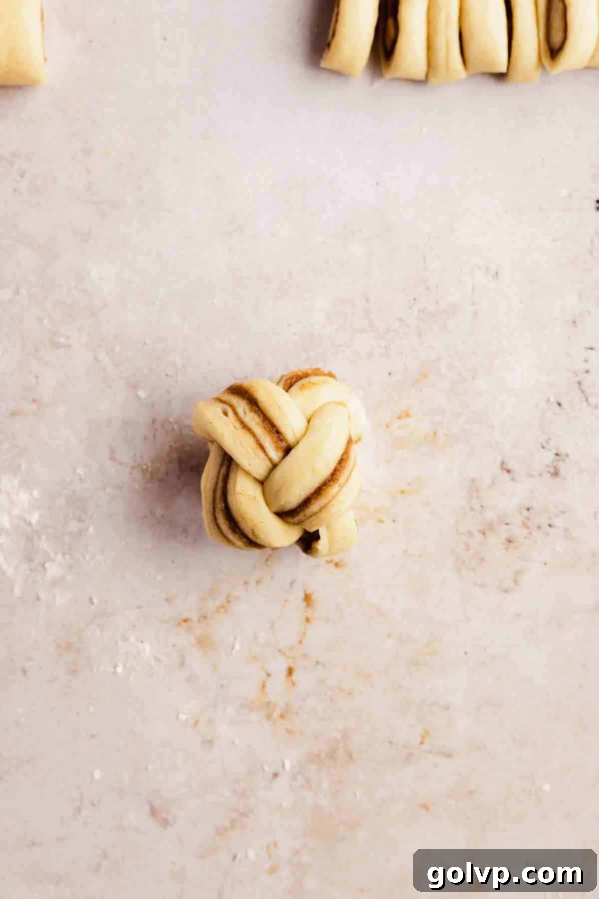Cinnamon Swirl Delights 9 Shaped braided cinnamon rolls placed in a muffin tin, ready for second rise