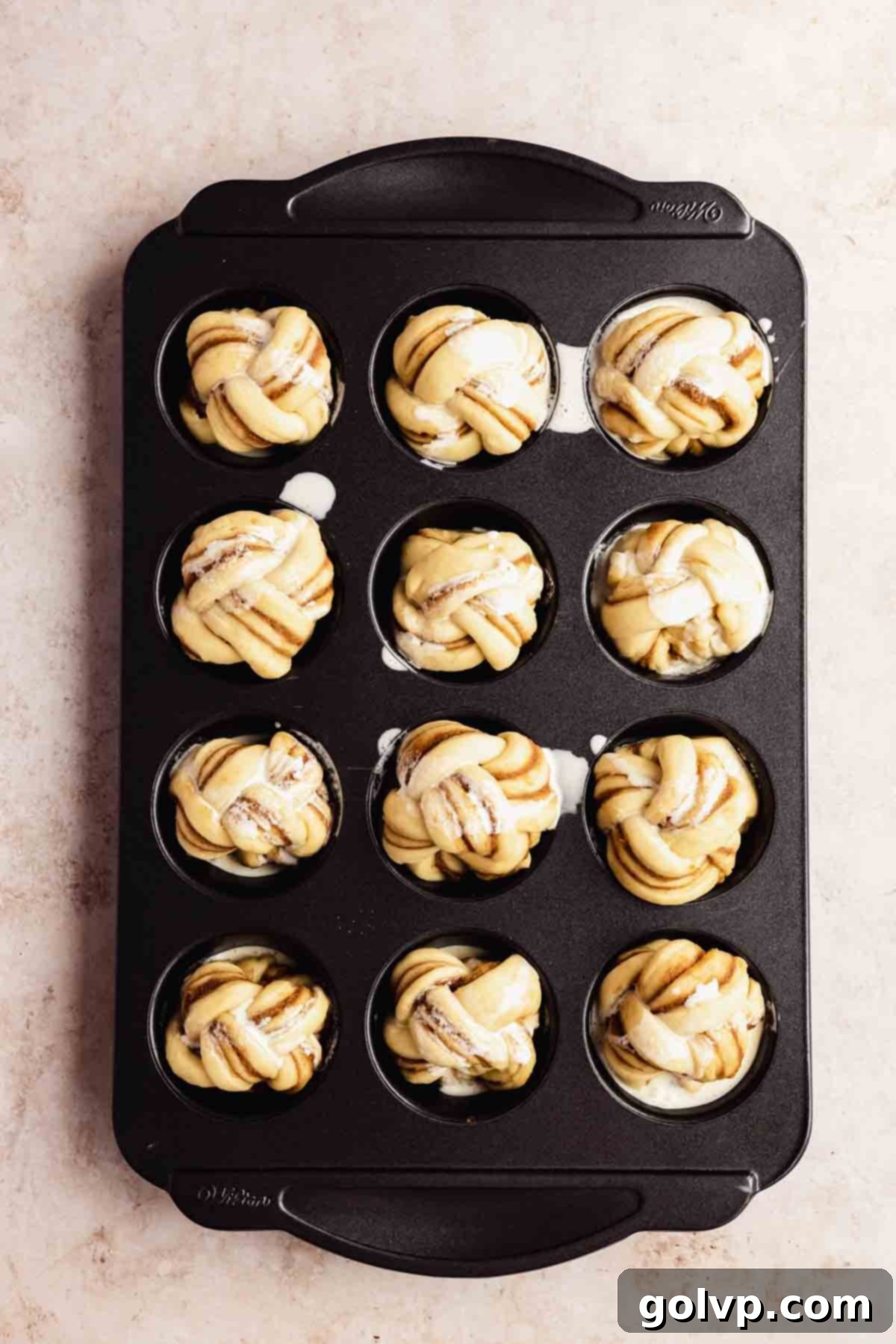Cinnamon Swirl Delights 10 Heavy cream being poured over risen cinnamon rolls in a muffin tin before baking