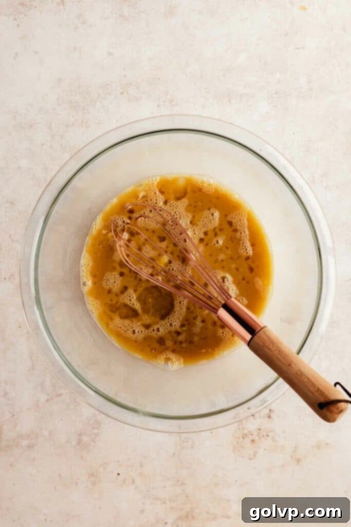 Tiramisu filling ingredients whisked together in a bowl, ready for cooking over a double boiler.