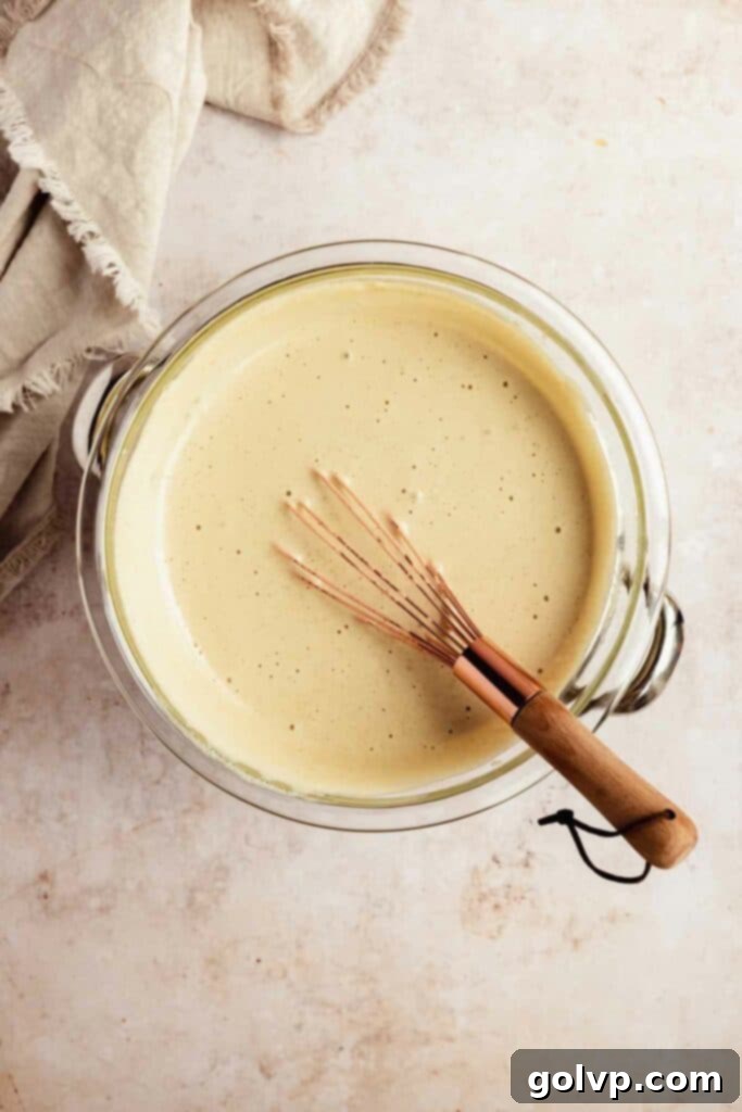 Whisking the tiramisu filling over a water bath, showing the beginning stages of thickening and foaming.