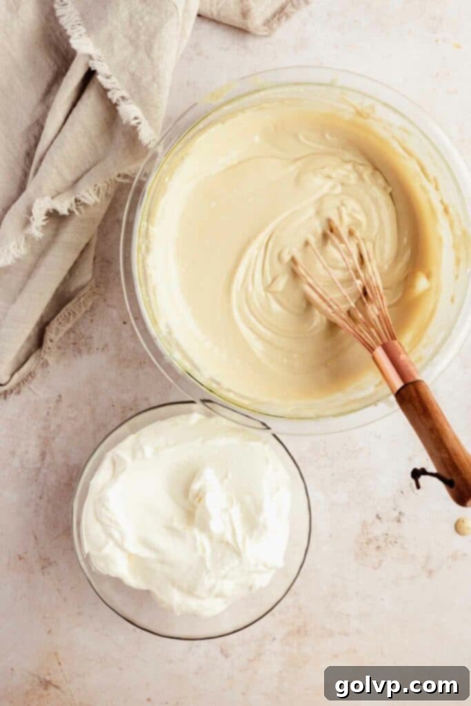Mascarpone cheese being added to the cooled tiramisu egg mixture, ready to be whisked until smooth.