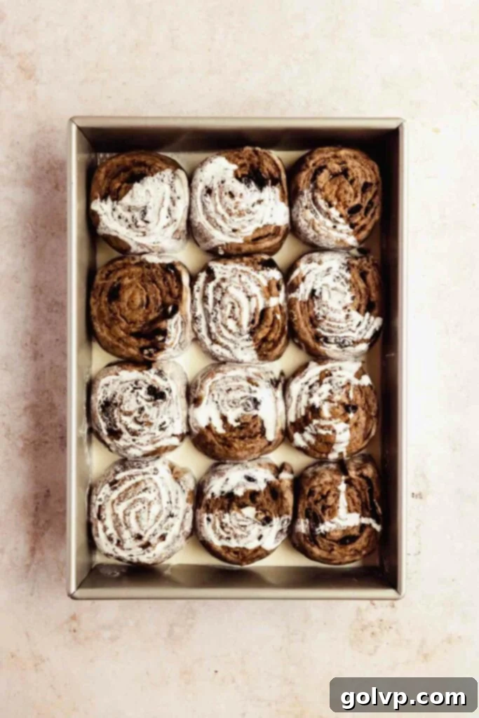 Step-by-step: Rolled and cut Cookies and Cream Cinnamon Rolls arranged in a baking tray, ready for heavy cream and baking.