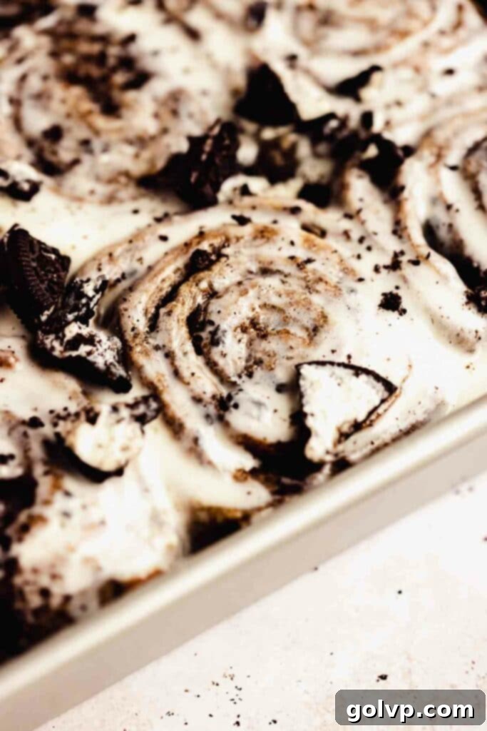 Decadent No-Knead Cookies and Cream Cinnamon Rolls 9 Freshly baked Cookies and Cream Cinnamon Rolls with melted cream cheese frosting and crushed Oreos in a baking tray.