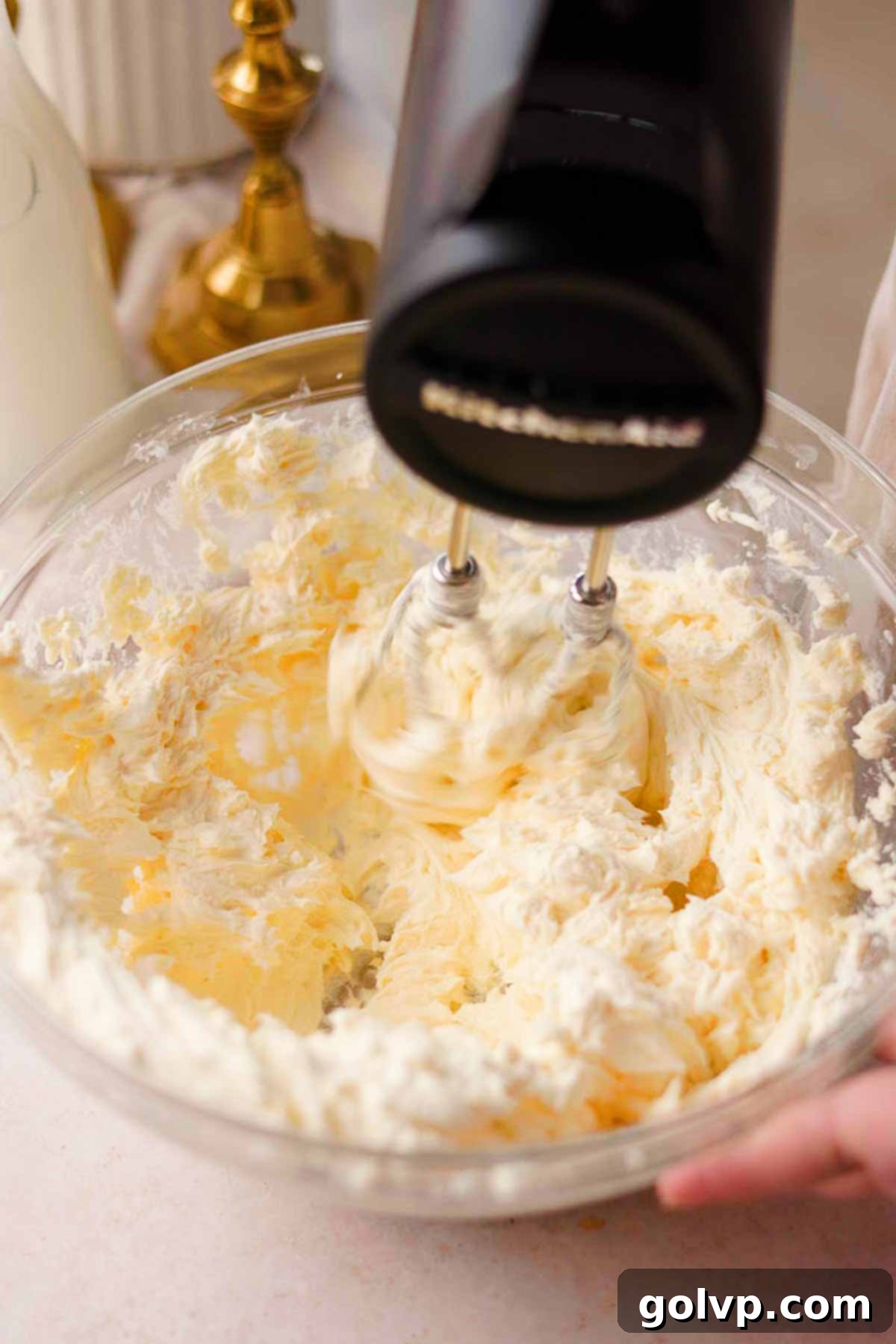 blending sugar and cream cheese with an electric mixer until creamy
