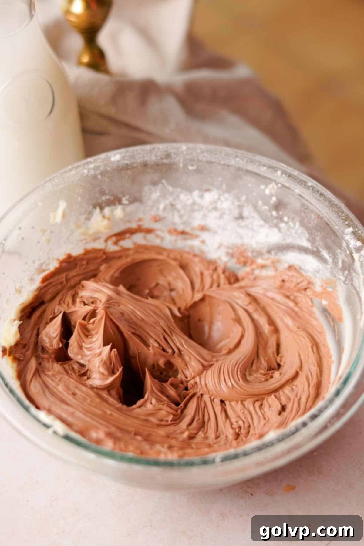 creamy light brown nutella frosting in glass bowl with powdered sugar on the sides