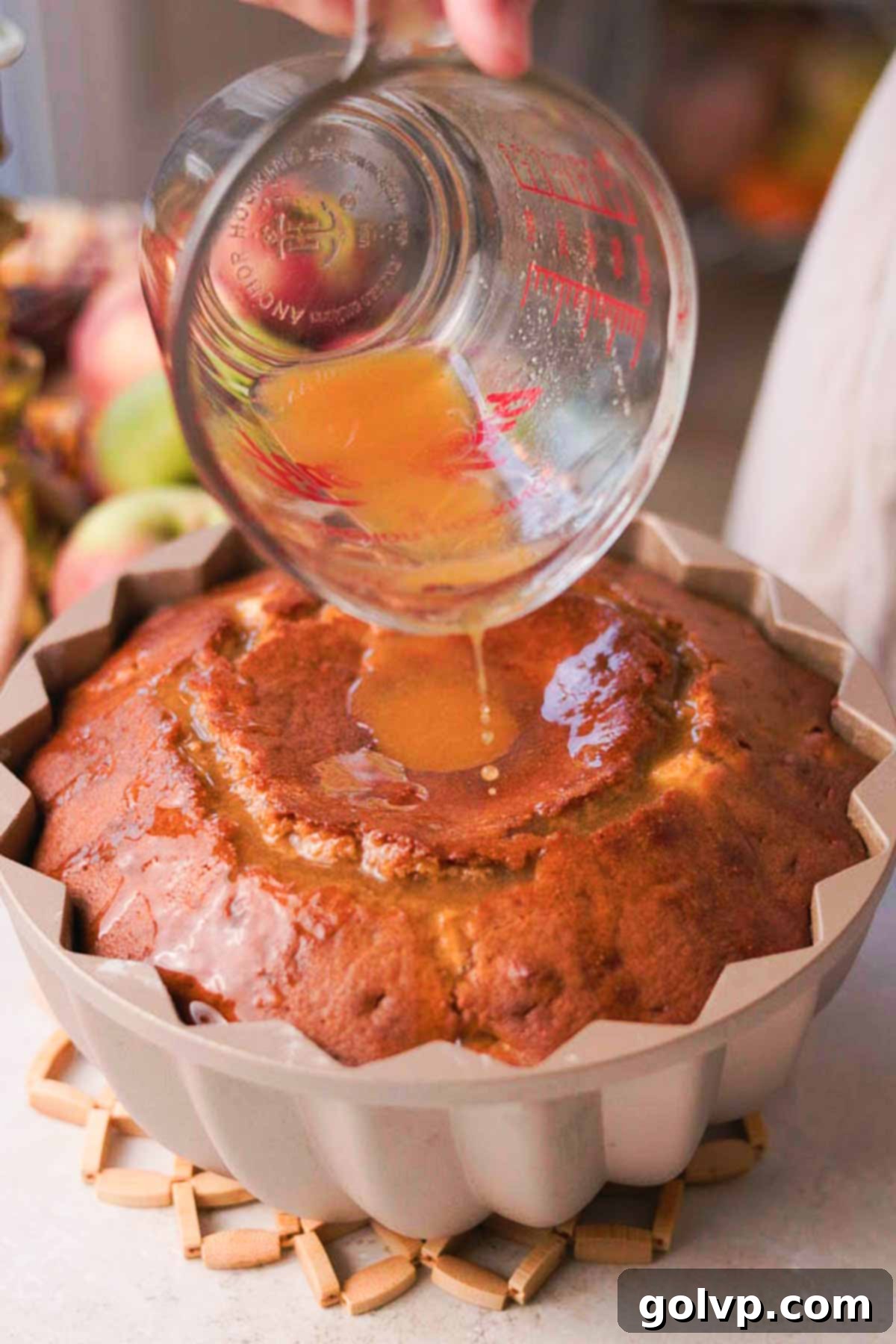 Spiced Autumn Apple Bundt 12 pouring apple cider syrup over baked apple cider bundt cake